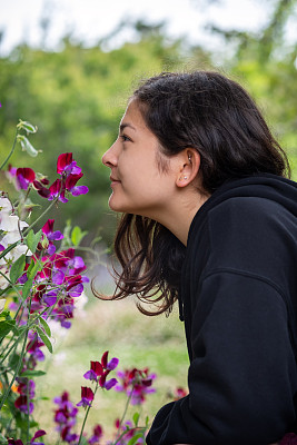 十几岁的女孩在有机花园里闻着芬芳的豌豆花