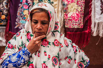 穿着传统服装的伊朗老年妇女在伊朗古村落Abyaneh的街道上出售纪念品
