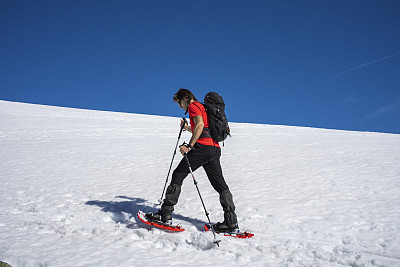 一个人穿着雪鞋在雪山上行走