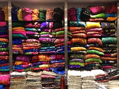 印度北方邦，Connaught Place，德里购物中心市场，彩色的印度织物材料堆放在货架上，丝巾，羊绒，床单和披肩