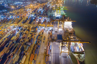 集装箱货轮的物流运输和货物与工作起重机桥在日出船厂，物流进出口和运输行业背景