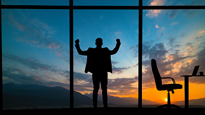 站在窗前的男人，背景是山上的夕阳