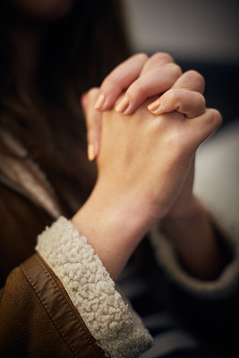 年轻女子紧握着祈祷或恳求的双手