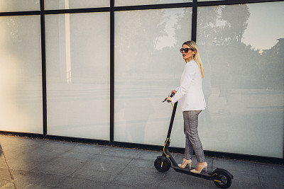 一个女商人骑着滑板车去上班