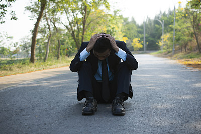 一个男人因为失望而坐在路上。生意失败了