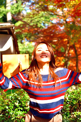 一名年轻的日本女子在东京的秋色公园里跳跃