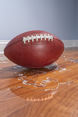 一个美式足球，地板上有破碎的玻璃