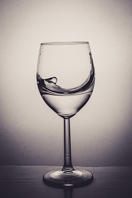玻璃杯里盛满水，溅起。