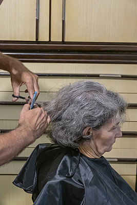 一位经验丰富的理发师正在为他的妻子理发
