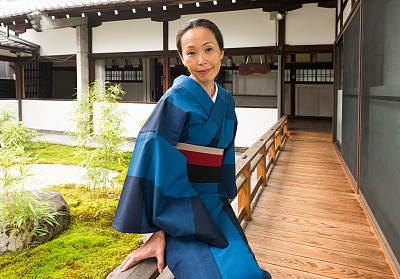 身着传统和服的日本成熟女性坐在京都寺外