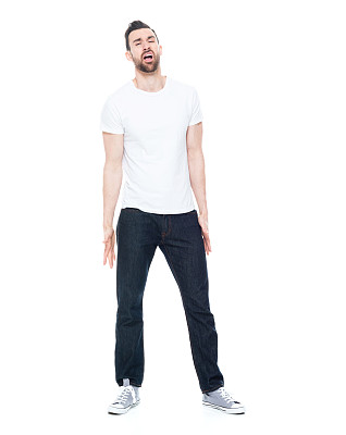 一名男子仅/全长30-39岁的成年英俊男子/白人男性/年轻男子面前穿着白色背景的牛仔裤谁是情绪紧张/沮丧/疲惫/冷淡的态度