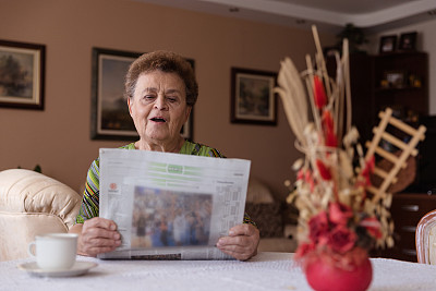 妇女在pansion放松在家里看报纸