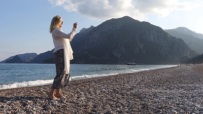 日出时分，一名女子在海滩上拍照