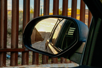 在美国和墨西哥之间的边境墙上看汽车的后视镜