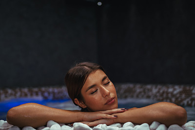 年轻女子在温泉中心的热水浴缸里放松