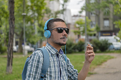 一名男子正在公园里抽烟和听音乐