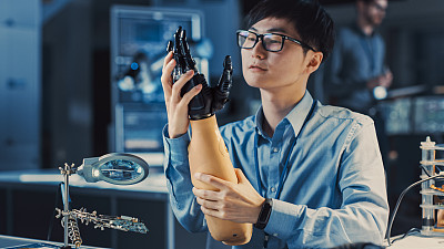 未来的假肢机器人手臂正在测试由专业的日本开发工程师在高科技研究实验室与现代计算机设备。他对结果很满意。
