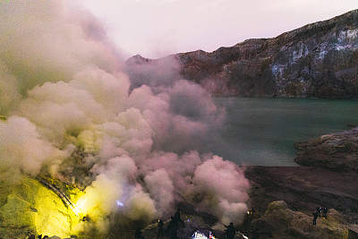 印度尼西亚东爪哇，伊真火山的壮观日出，蓝色的火焰和明亮的黄色硫磺蒸汽在绿松石湖之上