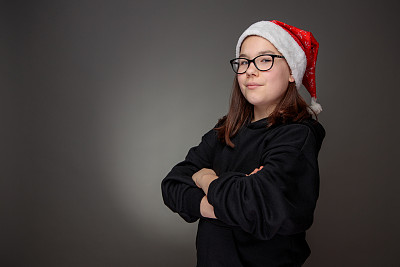 自信的少女，长头发，红色圣诞老人帽，黑色运动衫和眼镜