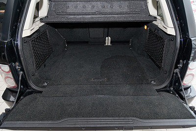 打开一辆越野车的空后备箱，在清洗和吸尘前，用一种特殊黑色材料的地毯地垫准备装入行李。汽车服务行业。