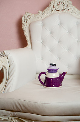 复古椅子上紫色茶壶上的蓝莓纸杯蛋糕