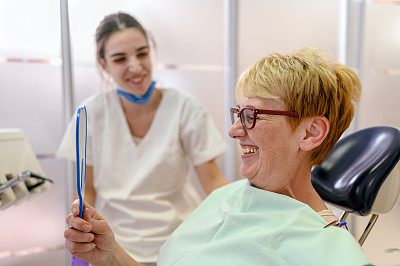 牙医对着镜子向病人展示她的新微笑