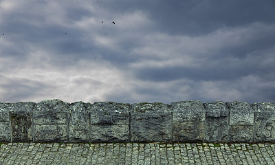 铺好的路石头栅栏前景框架对象在穆迪戏剧性多云暴风雨的天空背景风景与飞行的鸟壁纸背景空间复制或您的文字在这里