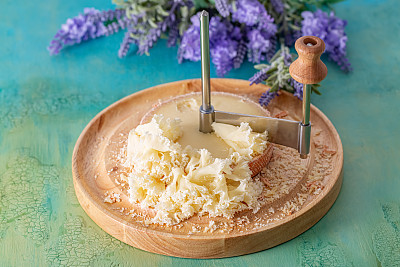 法国奶酪和尚头与丁香花瓣切成薄片，放在木制的圆形表面上。束薰衣草。