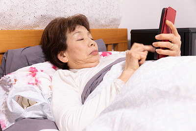 老年妇女在床上测量体温