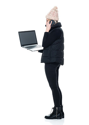 白人年轻女性无袖站在白色背景下穿着裤子使用电脑