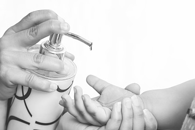 预防冠状病毒或COVID-19大流行，母亲把洗手液放在女儿手上。经常使用含酒精的洗手液洗手。家庭卫生的概念。