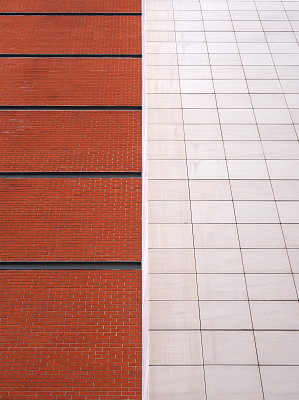 砖红砖砌成的墙，黑色线条被大块的白色现代石瓦分割成两半
