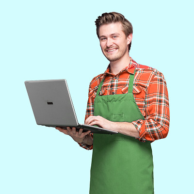 白人男性咖啡师站在蓝色背景下穿着伐木工衬衫使用笔记本电脑