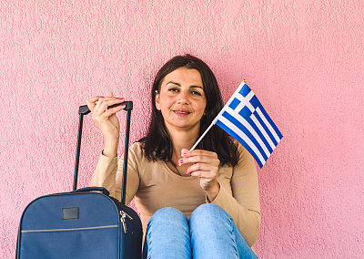 拿着旅行袋和希腊国旗的女人
