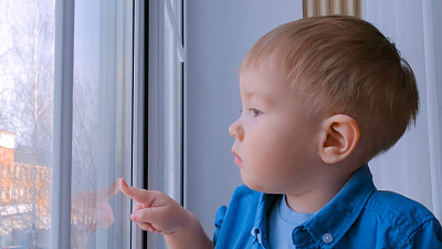 沉思的小男孩望着窗外