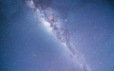 山上有银河和粉红的光。晚上多彩的景观。夏天的星空和山峦。美丽的宇宙。太空背景与星系。旅游的背景