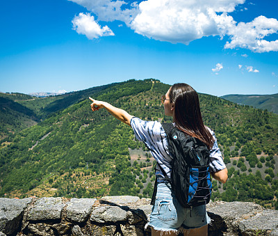 年轻女子背着背包在山里户外旅行