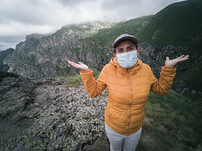 回归自然。新的标准。一个女人独自旅行者的肖像与保护性面具在她的脸上徒步在山上。2019冠状病毒病大流行期间，阳光明媚的户外享受。