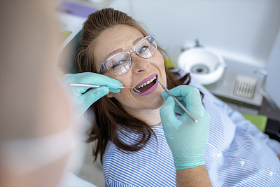 牙医使用挖掘机镰刀探针进行牙科检查
