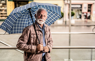 老人在城市的一个雨天。
