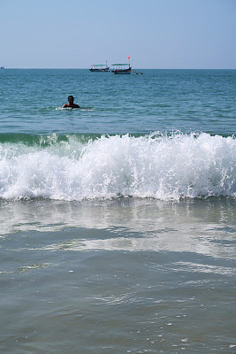 在印度果阿的Palolem海滩，一名印度男子在海滩度假，当海浪翻滚到沙滩上时，他坐在印度洋上戏水