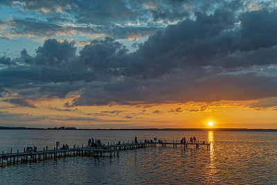 人们的剪影在码头湖边在黄昏与雄伟的云彩景观日落与雄伟的云彩景观