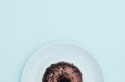 蓝色盘子和蓝色背景的巧克力甜甜圈。