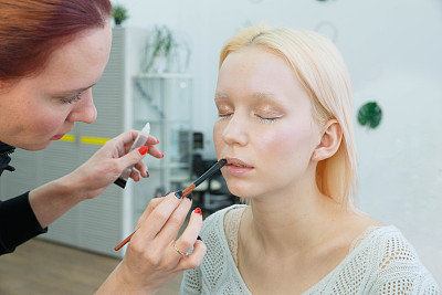 化妆的过程。化妆艺术家用画笔在模特脸上工作。