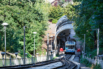 蓝色和白色的缆索在较低的车站搭载乘客，周围是夏季的绿色公园。