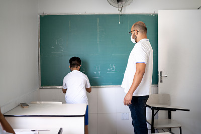 学生戴着口罩在黑板上做数学题