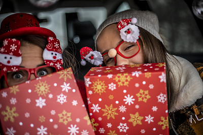 两个年轻的女人拿着新年礼物-两个年轻的女人拿着新年礼物-新年礼物和一个聚会在车里