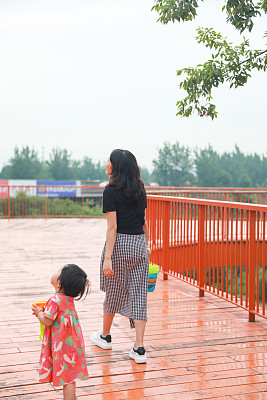 一个中国女孩和她的妈妈走在一条红脚小路上
