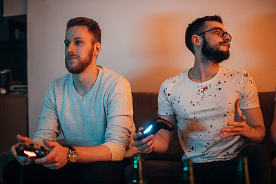 两个男人在玩电子游戏，玩得很开心
