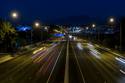 宽阔的公路视野与城市和山区在夜间的背景